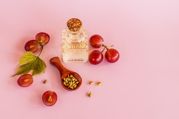 Óleo de semente de uva orgânico em uma garrafa de vidro em relevo leve com fundo rosa cortiça o conceito de massagem hidratante de cuidados naturais