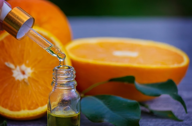 Óleo essencial de laranja em uma garrafa, pedaços de frutas frescas na superfície