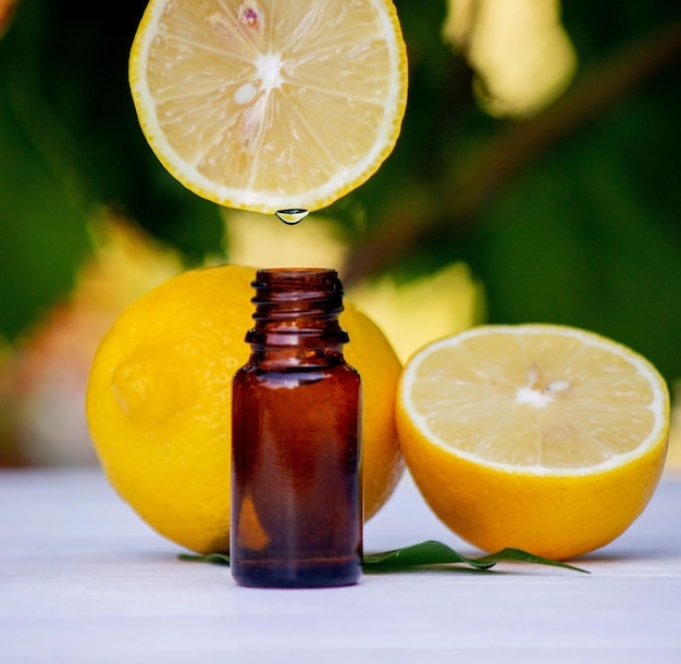 óleo essencial de limão e fruto de limão em uma tábua branca de madeira Foco seletivo
