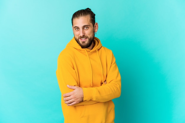 Olha jovem com cabelo comprido que se sente confiante, cruzando os braços com determinação.