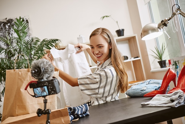 Olha o que eu tenho sorridente blogueira de moda fazendo uma resenha de vídeo sobre camisa branca em um