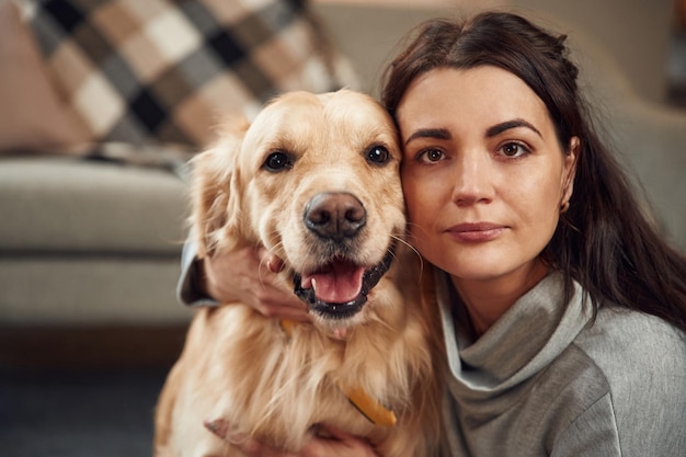 Olhando para a câmera A mulher está com o cachorro golden retriever em casa