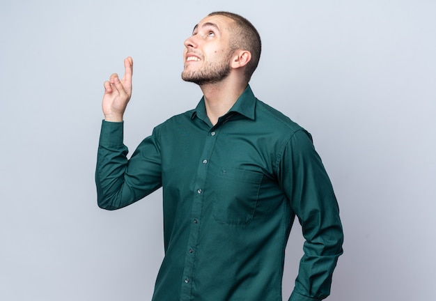 Olhando para cima, um rapaz bonito de camisa verde cruzando os dedos