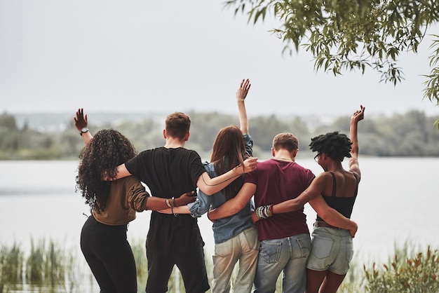 Olhando para o lago. as pessoas fazem uma festa lá fora. amigos de várias etnias se encontram no fim de semana.