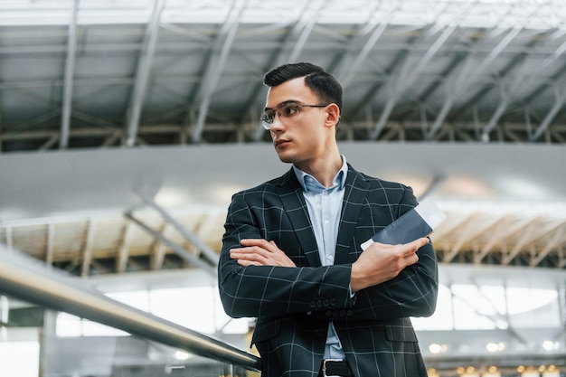 Olhar sério Jovem empresário em roupas formais está no aeroporto durante o dia