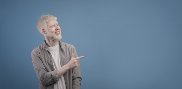 Olhe de lado jovem albino apontando o dedo para o lado e mostrando o espaço de cópia para o texto do anúncio azul