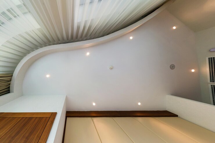 Foto olhe para cima no teto suspenso com lâmpadas de halogênio e construção de drywall com sensor de alarme de incêndio em sala vazia em apartamento ou casa teto extensível branco e forma complexa