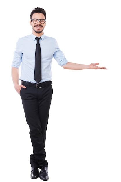 Olhe para isso! Comprimento total de um jovem bonito de camisa e gravata apontando para longe e sorrindo