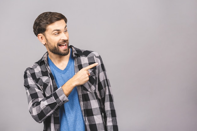 Olhe para lá! Feliz jovem bonito em casual apontando para fora e sorrindo em pé.