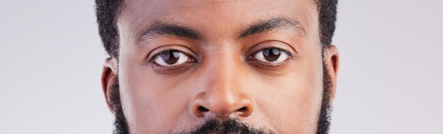 Foto olhos de homem negro e retrato de rosto em estúdio para foco de visão e expressão séria para encarar um homem africano em um fundo cinza para determinação de visão e consciência de identidade única