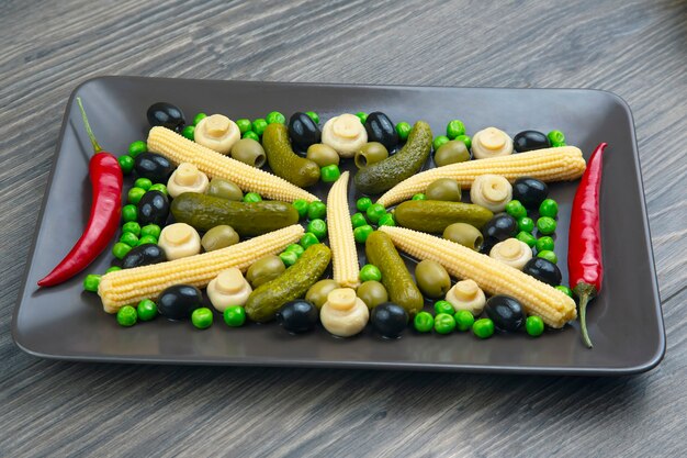 Oliven, eingelegte Gurken, Pfeffer, Pilze und Mais in einem Salat auf einem Teller. Essen und Gemüse. Diät und Gewichtsverlust