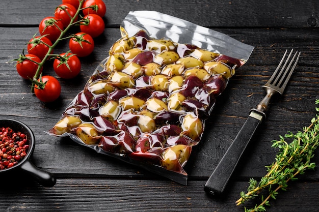 Oliven in Vakuumverpackung für Supermarkt-Set, auf schwarzem Holztischhintergrund