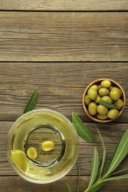 Olivenöl mit Olive auf grauem Hintergrund mit Kopienraum. Vertikales Foto