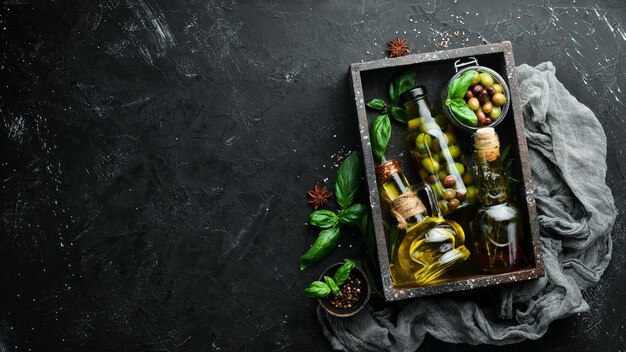 Olivenöl, Oliven und Gewürze auf schwarzem Steinhintergrund Draufsicht Freier Platz für Ihren Text