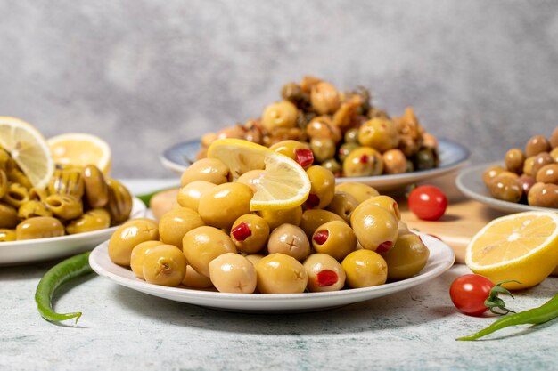 Olivensorten Sortiment aus schwarzen und grünen Oliven auf einem Teller auf grauem Hintergrund, niedriger Blickwinkel