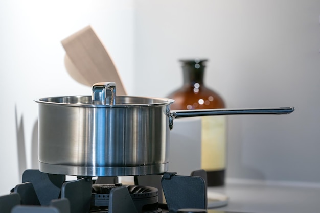 Olla de acero inoxidable en estufa plana electrónica moderna con poca luz en la sala de la cocina