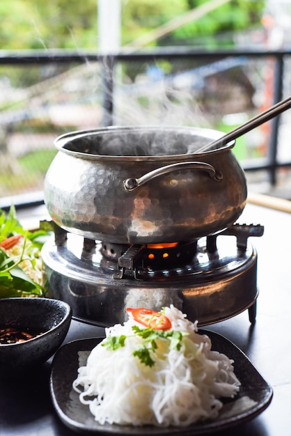 Olla caliente coreana con carne de pollo y fideos sobre fondo negro