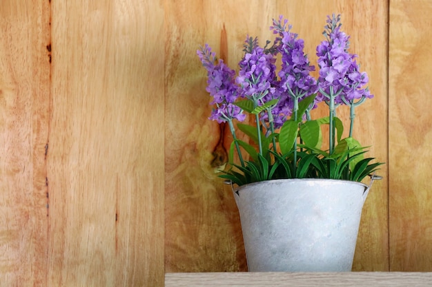 Olla de cerámica blanca de ramo de flores moradas en la mesa de madera con interior de pared de madera y objeto