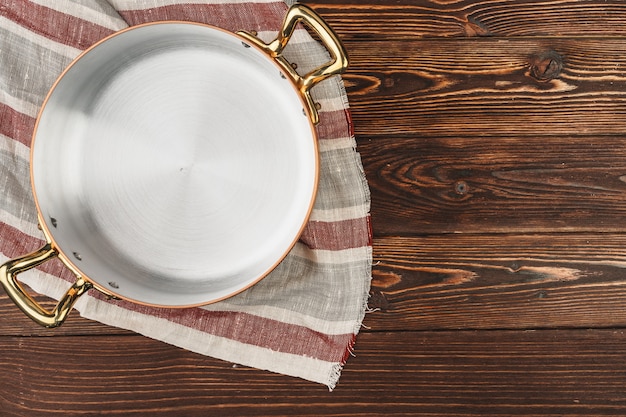 Olla de cobre con mantel chekered en mesa de madera