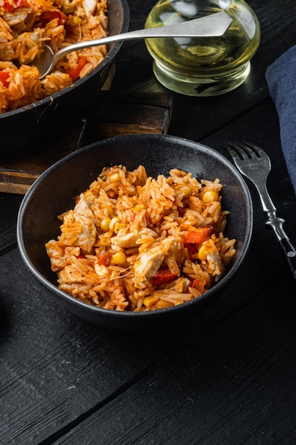 Una olla de enchilada de pollo, cazuela de arroz, sobre fondo de mesa de madera negra