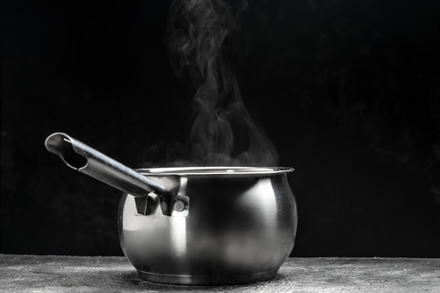 Olla humeante sobre fondo negro Concepto de comida caliente Tazón de vapor caliente de sopa caliente con humo