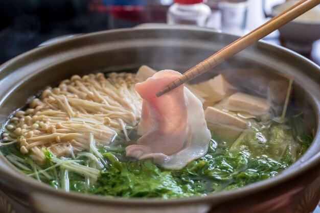 Una olla de ramen con un trozo de carne encima