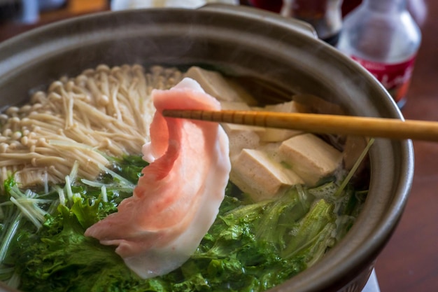 Una olla de ramen con un trozo de carne rosa