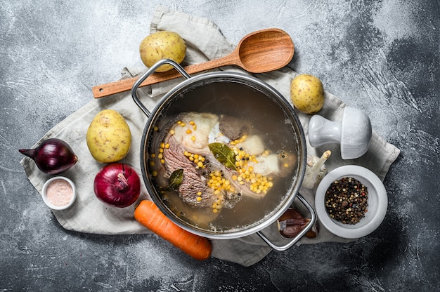 Olla con ternera en el hueso. Ingredientes para sopa, verduras y especias. Vista superior