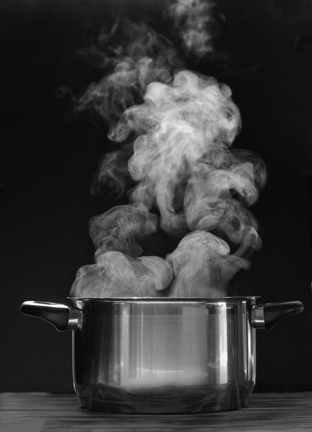 Foto olla de vapor en el fondo negro humo por encima de la olla de sopa hirviendo