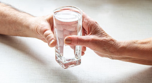 Oma gibt Großvater ein Glas Wasser. Selektiver Fokus. Lebensmittel.