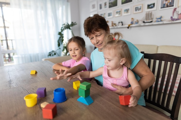 Oma spielt mit ihren Enkeln zu Hause am Tisch