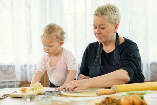 Oma und Enkelin schneiden Teigblatt mit Keksform-Backstunde