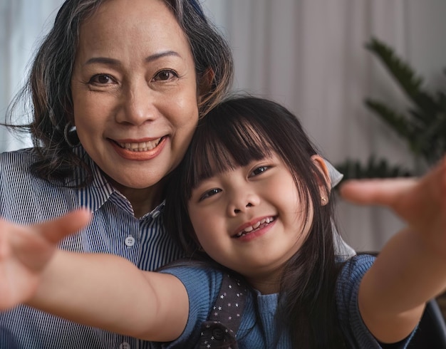 Oma und Enkelin sitzen glücklich zusammen und spielen im Wohnzimmer