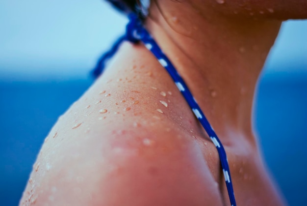 Ombro bronzeado feminino em um maiô com gotas de água do mar