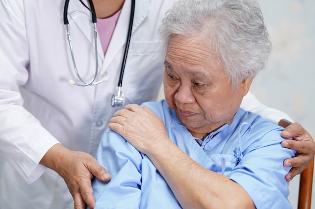 Ombro sênior asiático da dor da mulher no hospital.