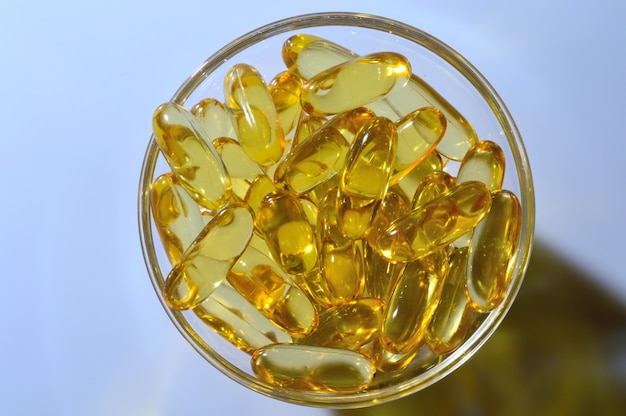 Omega-3- und Vitamin-D-Fischölkapseln in einer Glasplatte.