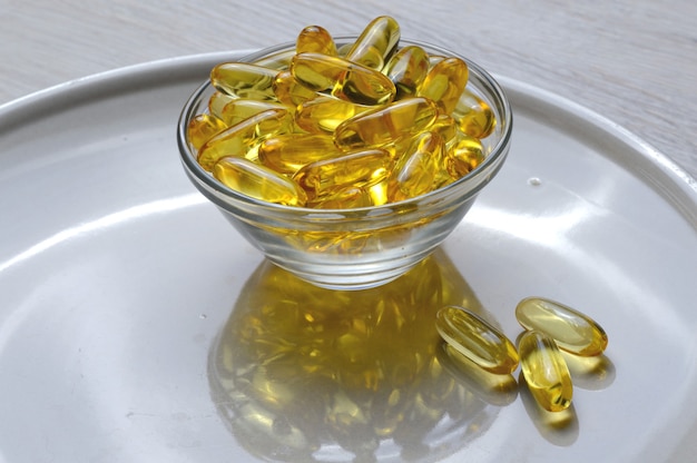 Omega-3- und Vitamin-D-Fischölkapseln in einer Glasplatte.