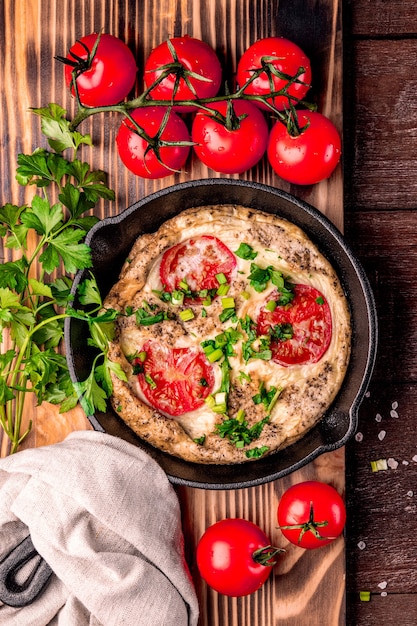 Omelete caseiro com tomate e ervas em uma panela, vista de cima