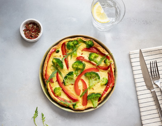 Omelete caseiro, delicioso com brócolis e pimenta vermelha em concreto cinza