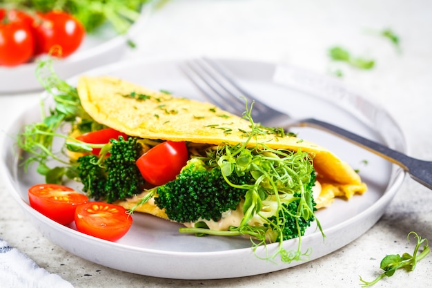 Omelete com brócolis, tomate e mudas. Conceito de comida vegetariana saudável.