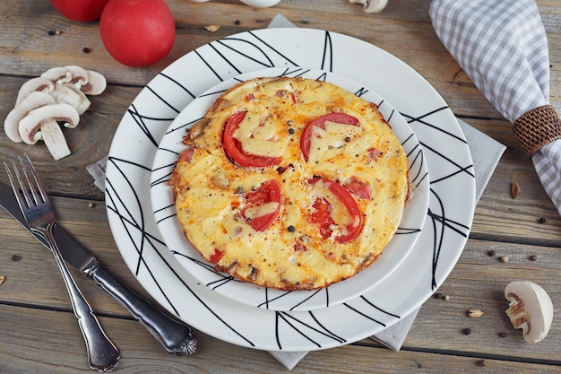 Omelete com cebola, tomate e cogumelos em lindos pratos brancos