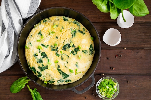 Omelete com cebolinha espinafre e queijo feta em uma frigideira de ferro fundido