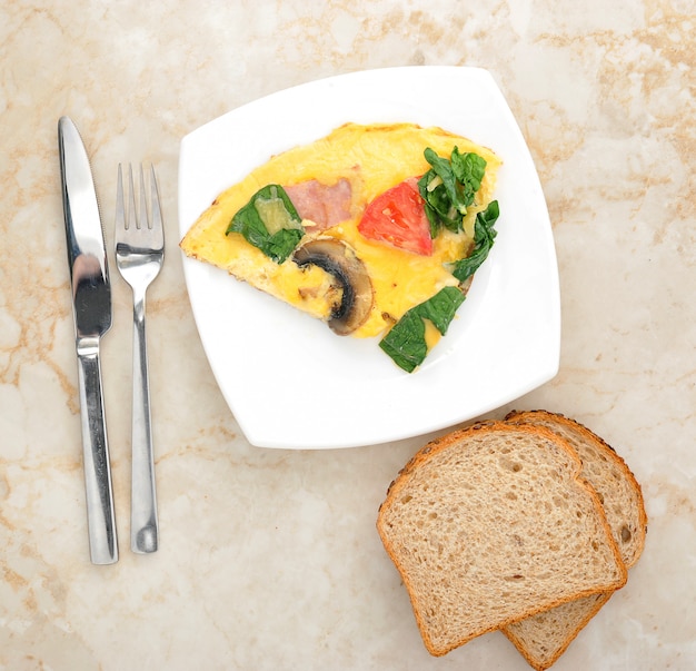 Omelete com espinafre, tomate e cogumelos no prato redondo