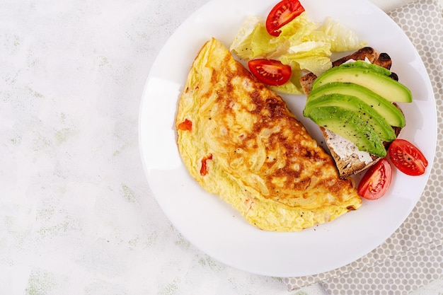 Omelete com tomate e torrada com abacate em prato branco Omelete italiano fritada Vista superior plana