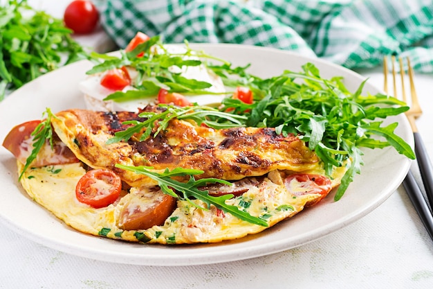 Omelete com tomate, queijo e ervas verdes no prato. frittata - omelete italiana.