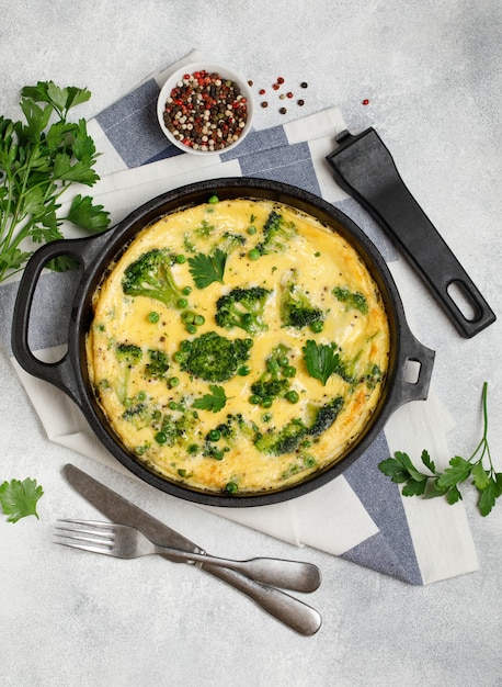 Omelete com vegetais verdes, brócolis e ervilha verde em uma frigideira