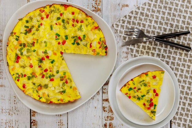 Omelete de café da manhã com couve-flor e pimentão com garfo e faca na superfície branca