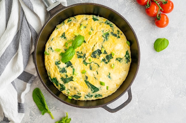 Omelete de cima com espinafre, cebolinha e queijo feta em uma frigideira de ferro fundido