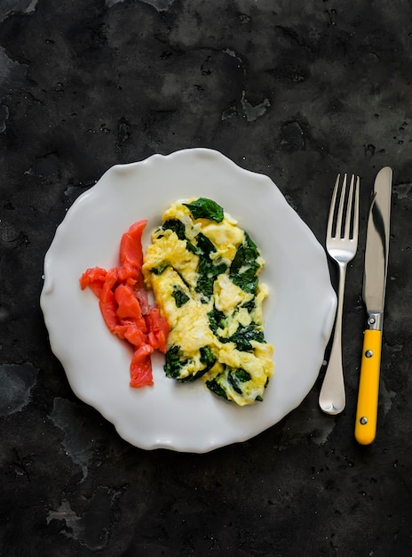 Omelete de espinafre e salmão ligeiramente salgado delicioso café da manhã brunch em um fundo escuro vista de cima