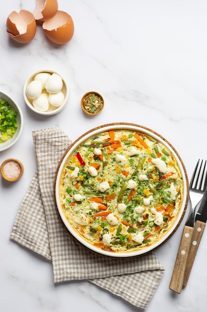 Foto omelete de fritada de ovo plana com legumes da estação e queijo no prato no fundo de mármore branco conceito de comida de café da manhã saudável vista superior